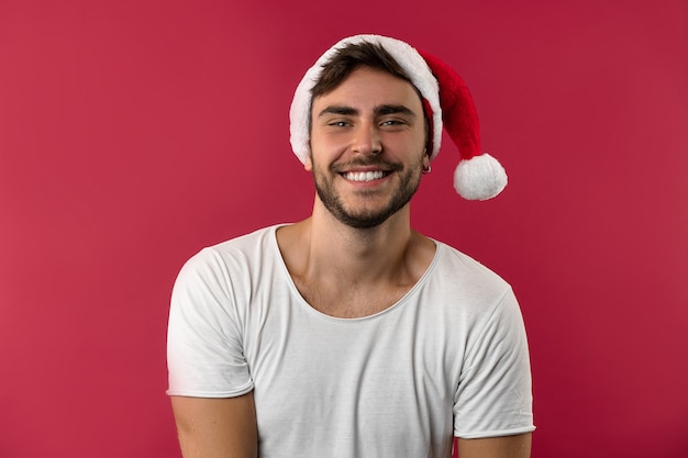 Jonge knappe man in een witte t-shirt en kerstmuts