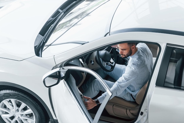 Jonge knappe man in formele kleding zit in gloednieuwe auto