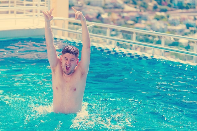 Jonge knappe man in het zwembad zonlicht Toned