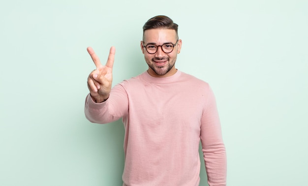 Jonge knappe man lacht en ziet er vriendelijk uit, toont nummer twee of seconde met de hand naar voren, aftellend