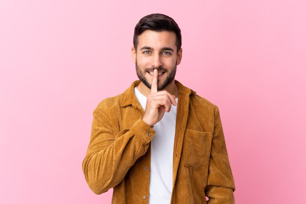 Jonge knappe man met baard die een corduroy jasje draagt dat stilte gebaar doet