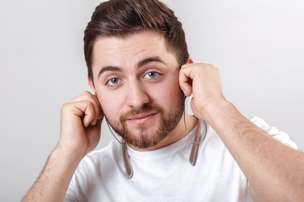 Jonge knappe man met baard in tshirt luisteren naar muziek op koptelefoon