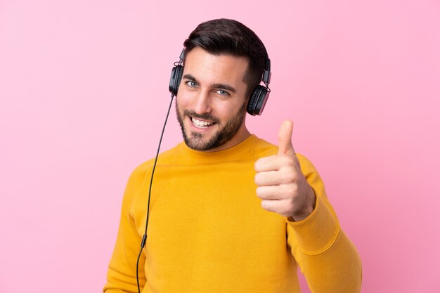 Jonge knappe man met baard luisteren muziek over roze