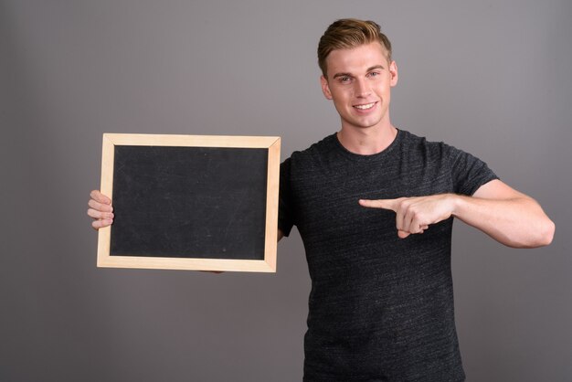 Jonge knappe man met blond haar grijs shirt dragen op grijze muur