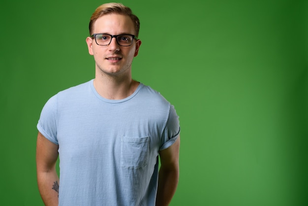 Jonge knappe man met blond haar tegen een groene achtergrond