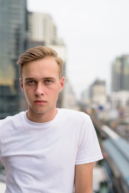 Jonge knappe man met blond haar tegen uitzicht over de stad