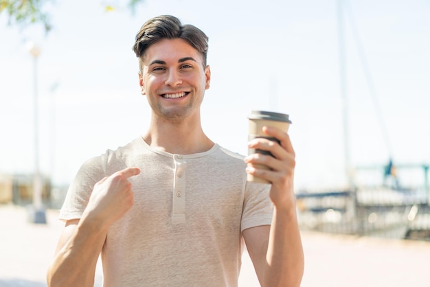 Jonge knappe man met een afhaalkoffie buitenshuis met een verrassende gezichtsuitdrukking