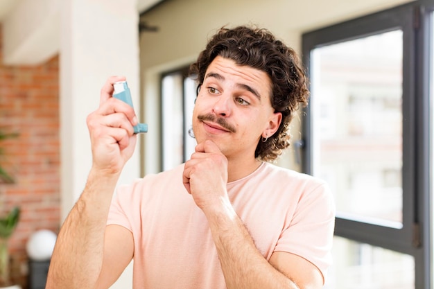 Jonge knappe man met een astma-inhalator in het interieur