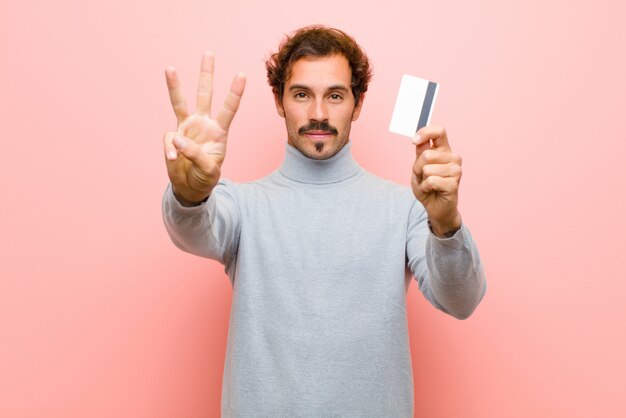 Jonge knappe man met een creditcard roze platte muur