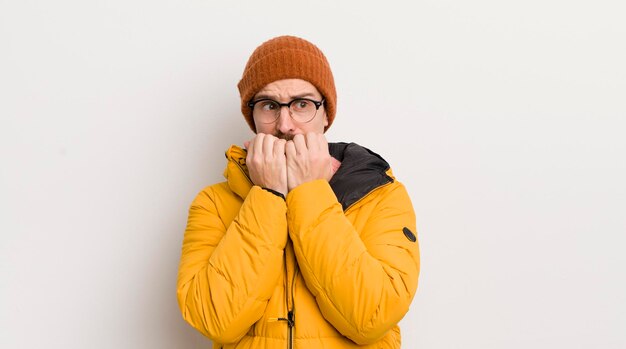 Jonge knappe man met een jas tegen de witte muur