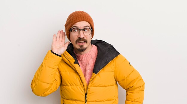 Jonge knappe man met een jas tegen de witte muur