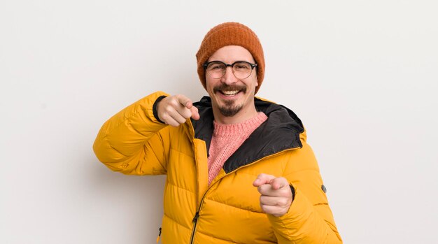 Jonge knappe man met een jas tegen de witte muur