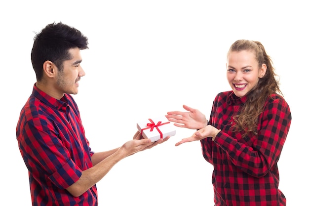 Jonge knappe man met een jonge vrouw in een rood geruit overhemd met een wit cadeau met rood lint