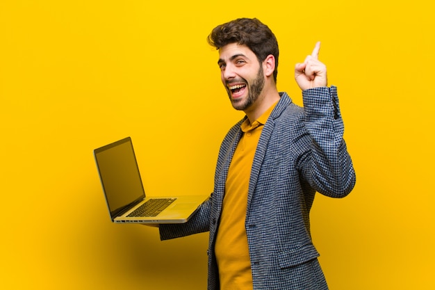 Jonge knappe man met een laptop tegen oranje achtergrond