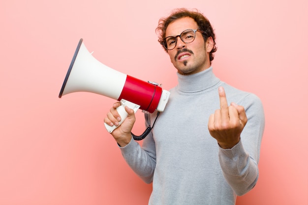 Jonge knappe man met een megafoon tegen roze platte muur