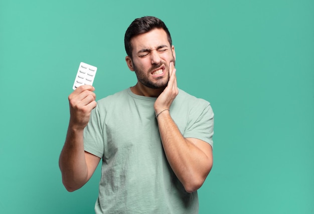 Jonge knappe man met een pillen tablet ziekte of pijn concept