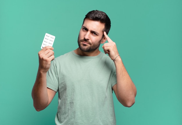 Jonge knappe man met een pillentablet. ziekte of pijn concept