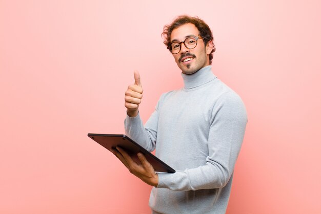 Jonge knappe man met een tablet roze platte muur