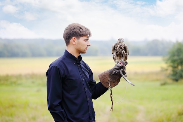 Jonge knappe man met een valk op zijn arm