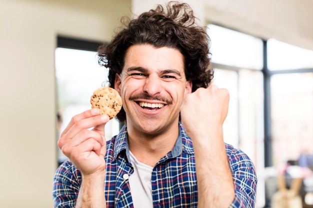 Jonge knappe man met een zelfgemaakt koekje in het interieur