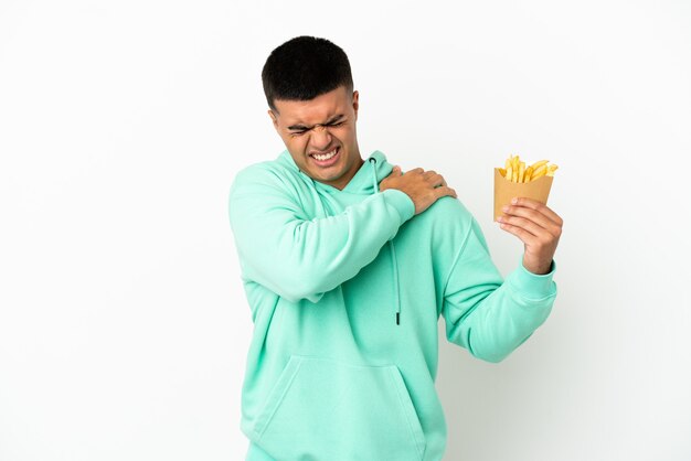 Jonge knappe man met gefrituurde chips over een geïsoleerde witte achtergrond die lijdt aan pijn in de schouder omdat hij moeite heeft gedaan