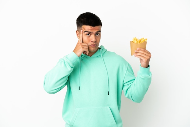 Jonge knappe man met gefrituurde chips over geïsoleerde witte achtergrond en denkt aan een idee