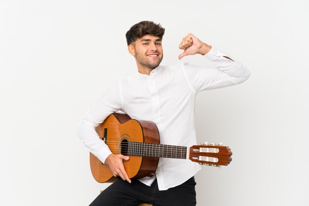 Jonge knappe man met gitaar over geïsoleerde witte trots en zelfvoldaan