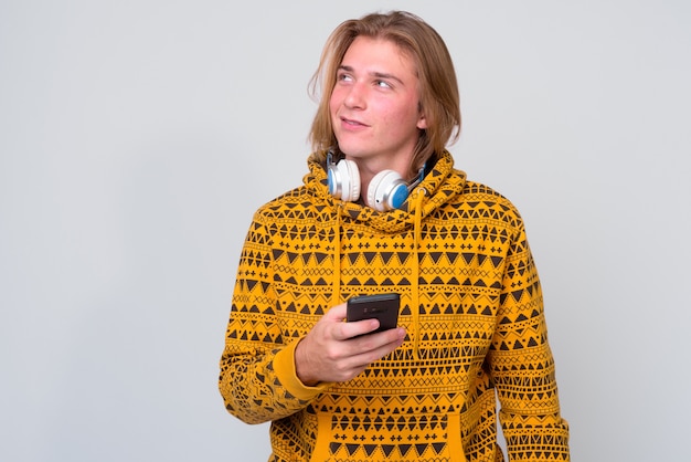 jonge knappe man met lang blond haar tegen witte muur