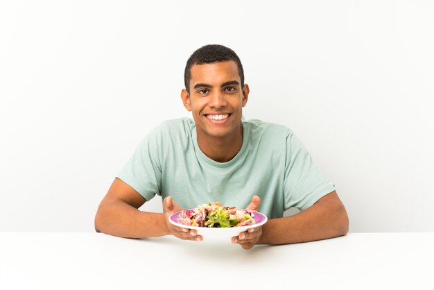 Jonge knappe man met salade in een tafel