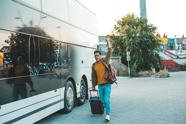 Jonge knappe man rent achter de bus aan die vertrekt. hij miste de bus en probeert hem te halen.