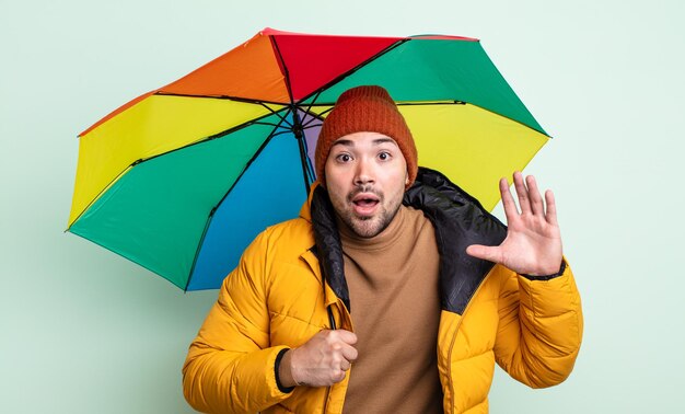 Jonge knappe man schreeuwen met handen omhoog in de lucht. regen en paraplu concept