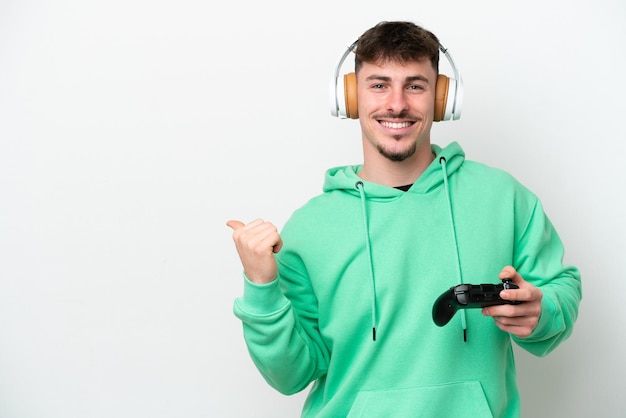Jonge knappe man speelt met een videogamecontroller geïsoleerd op een witte achtergrond die naar de zijkant wijst om een product te presenteren