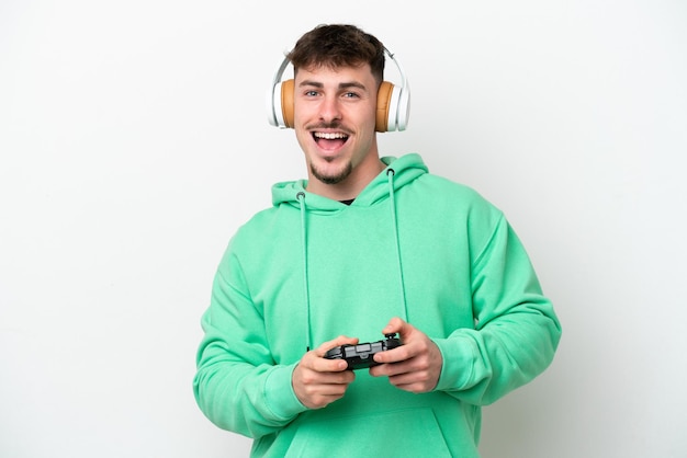 Jonge knappe man spelen met een video game controller geïsoleerd op een witte achtergrond met verrassing gezichtsuitdrukking