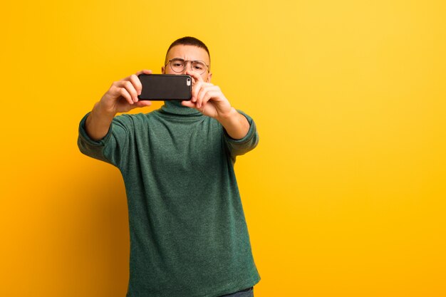 Jonge knappe man tegen platte muur met een slimme telefoon