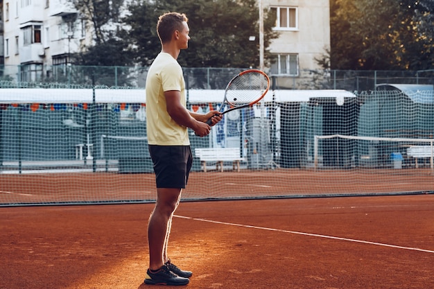 Jonge knappe man tennissen op de tennisbaan van klei