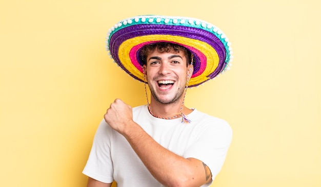 Jonge knappe man voelt zich gelukkig en staat voor een uitdaging of feest. mexicaanse hoed concept