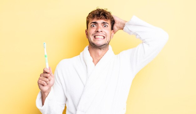 Jonge knappe man voelt zich gestrest, angstig of bang, met de handen op het hoofd. tandenborstel concept