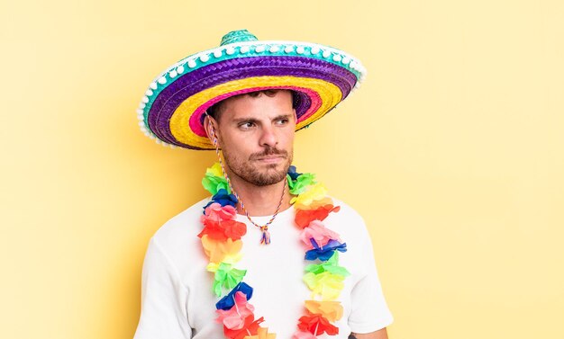 Jonge knappe man voelt zich verdrietig, overstuur of boos en kijkt opzij. Mexicaans feestconcept