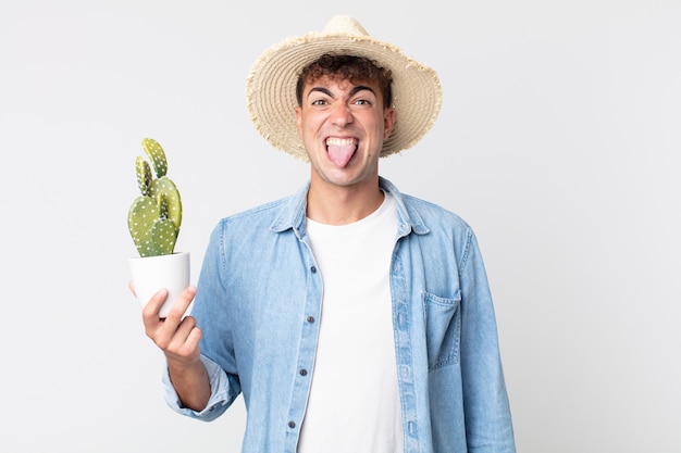 Jonge knappe man voelt zich walgelijk en geïrriteerd en tong uit. boer met een decoratieve cactus