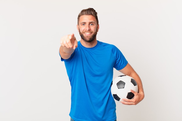 Jonge knappe man wijzend op de camera die jou kiest. voetbal concept