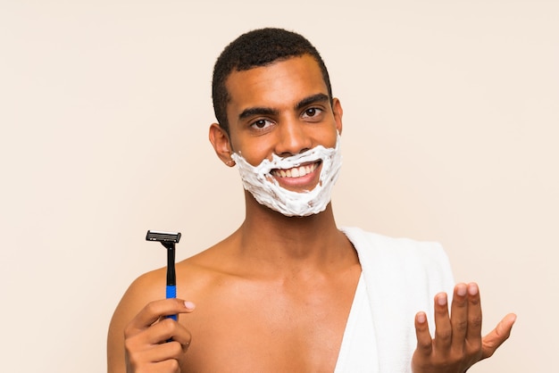 Jonge knappe man zijn baard scheren uitnodigend om te komen met de hand