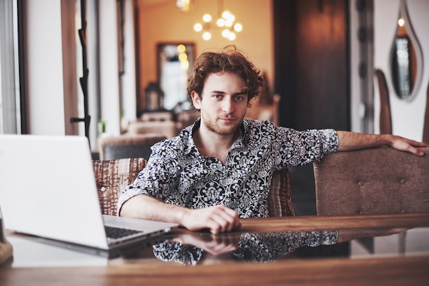 Jonge knappe man zitten in kantoor met een kopje koffie en werken aan project verbonden met moderne cybertechnologieën