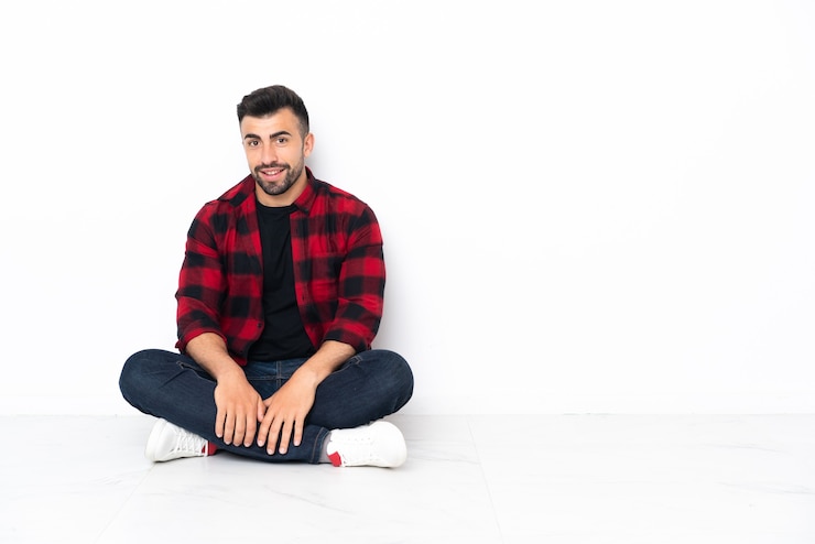 Foto jonge knappe man zittend op de vloer lachen