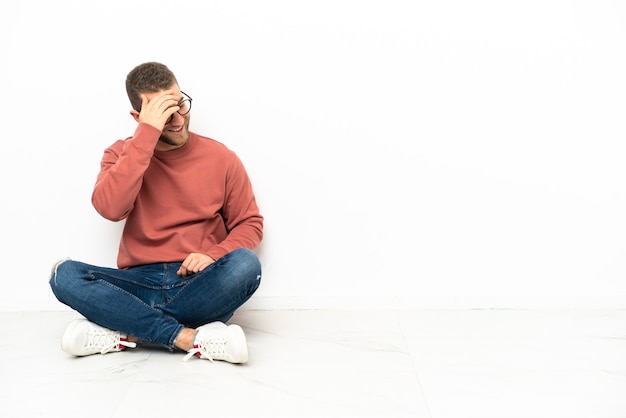 Jonge knappe man zittend op de vloer lachen