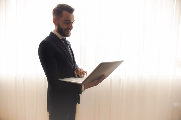 Jonge Knappe Ondernemer die Laptop met behulp van tegen Venster