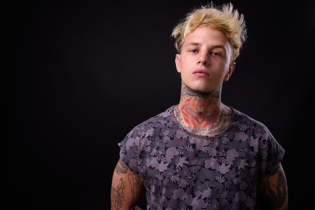 Jonge knappe opstandige man met blond haar en tatoeages