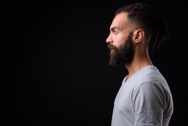 jonge knappe Perzische man met dreadlocks tegen zwarte muur