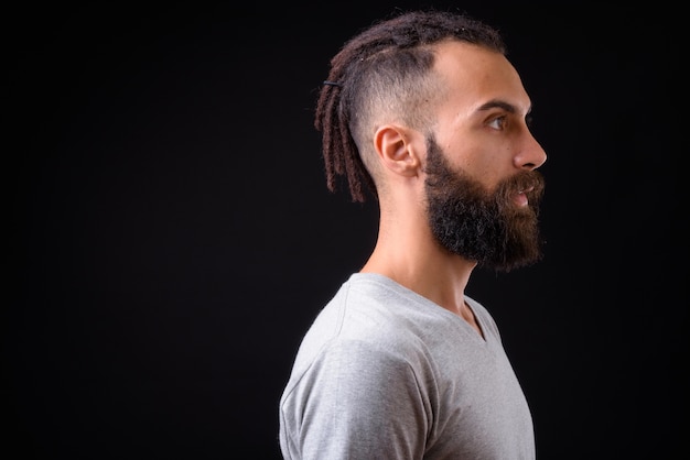 jonge knappe Perzische man met dreadlocks tegen zwarte muur