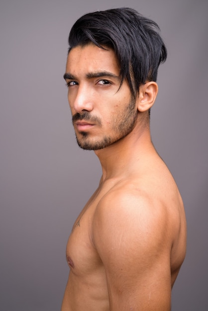 Jonge knappe Perzische man shirtless tegen een grijze achtergrond