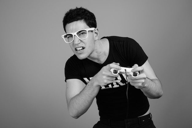 jonge knappe Perzische nerd man met bril tegen grijze muur in zwart-wit